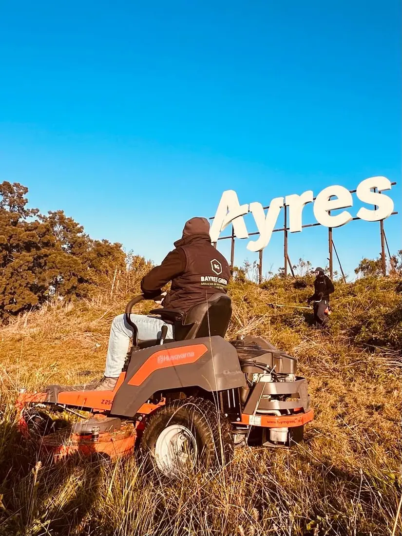 Corte con minitractor frente al cartel de Ayres